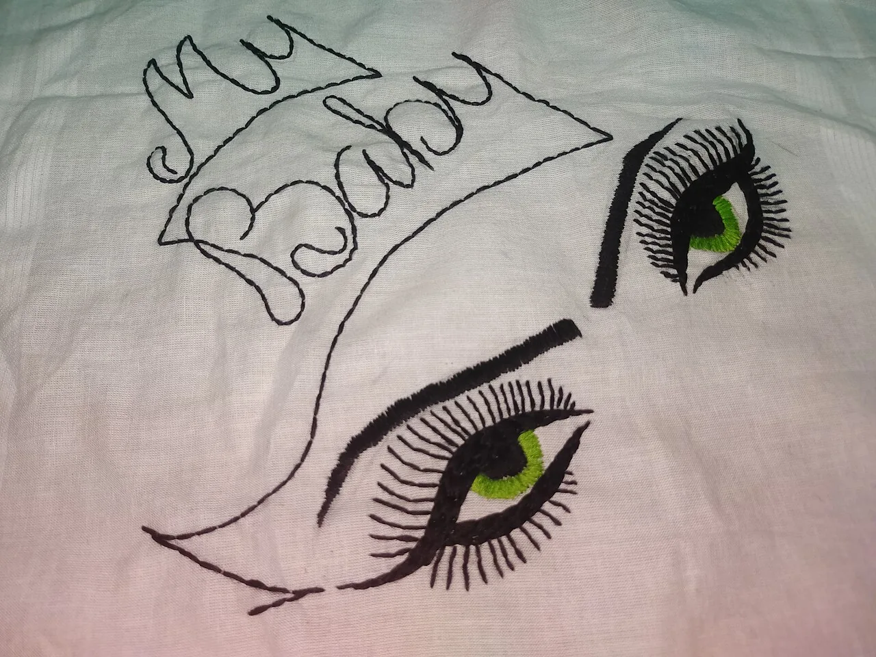 Broderie figurant des yeux sur une étoffe claire.